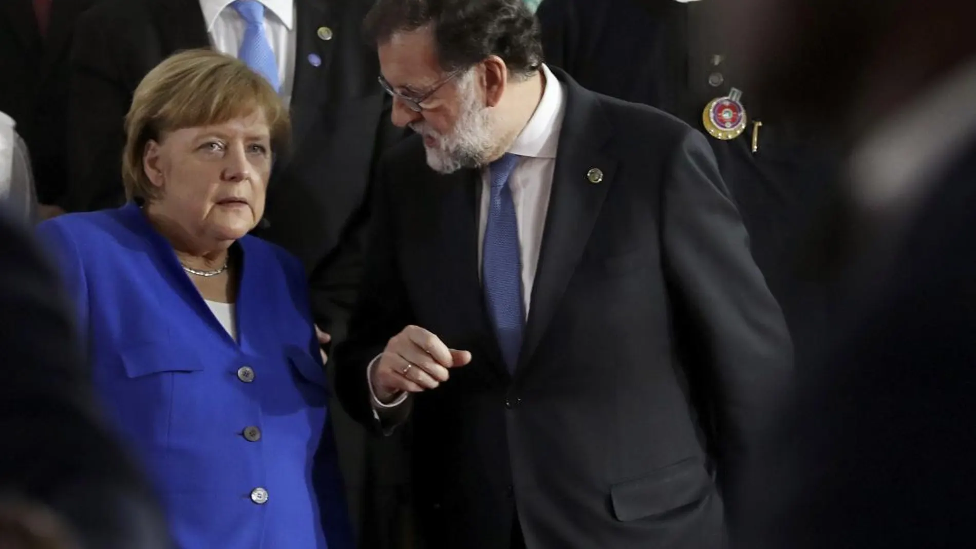 Mariano Rajoy conversa con la canciller alemana, Angela Merkel, durante la foto de familia de los asistentes a la V cumbre Unión Africana-Unión Europea que se celebra en Abiyán (Costa de Marfil)