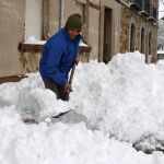 En la imagen un vecino de la localidad leonesa de Villamanín, en la zona norte de León, retira nieve a la entrada de su vivienda