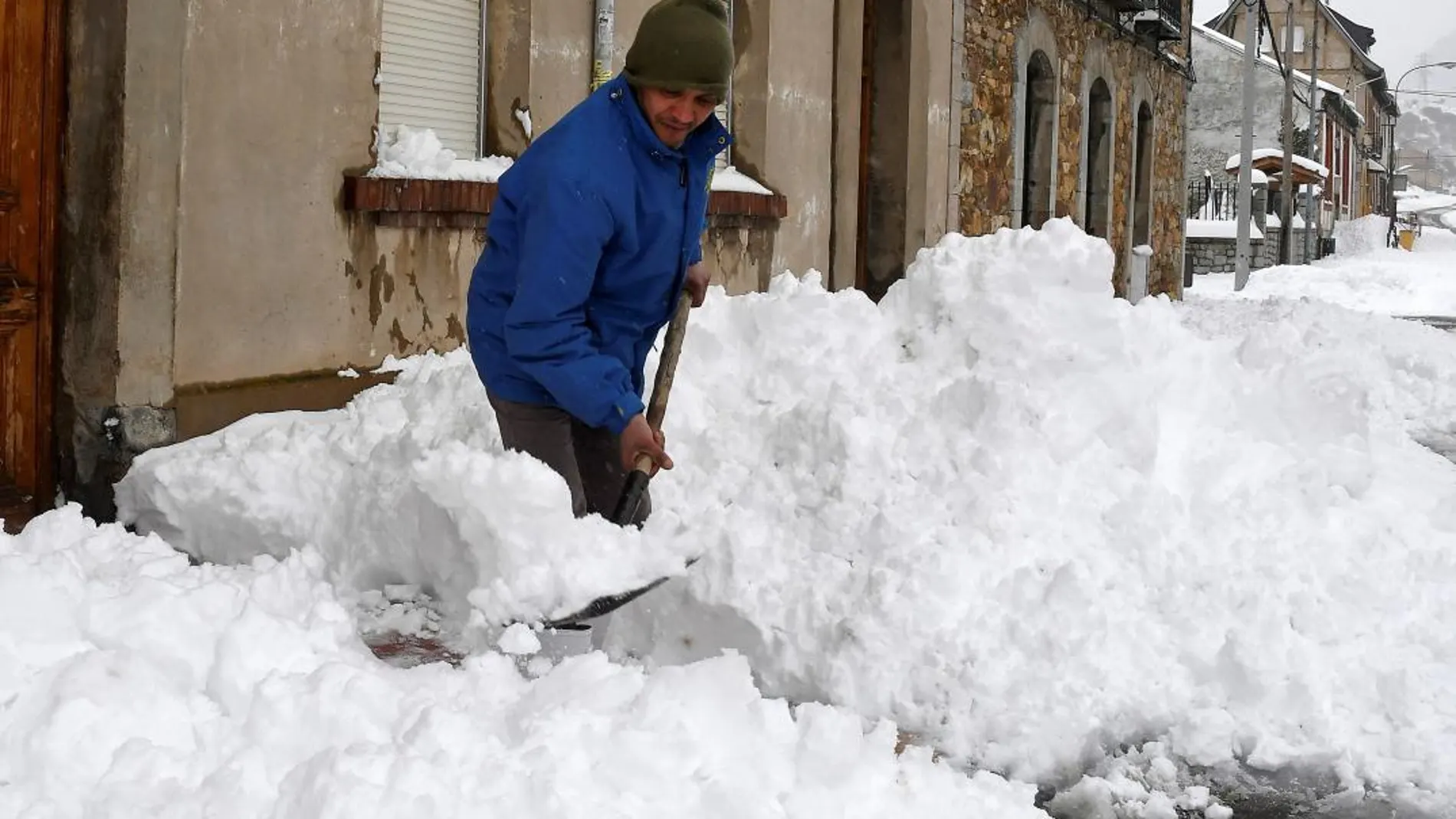 En la imagen un vecino de la localidad leonesa de Villamanín, en la zona norte de León, retira nieve a la entrada de su vivienda