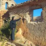 El sacerdote José Sala señala una de las ventanas de la iglesia de Valdegrulla en la que han sustraído piedras de sillería y rejas de forja