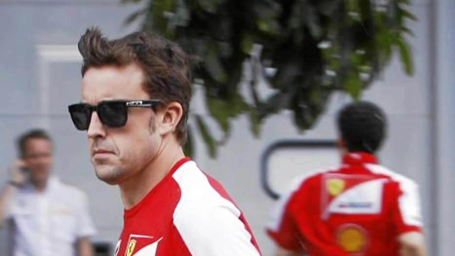 Alonso corre para protegerse de la lluvia en el circuito de Sepang