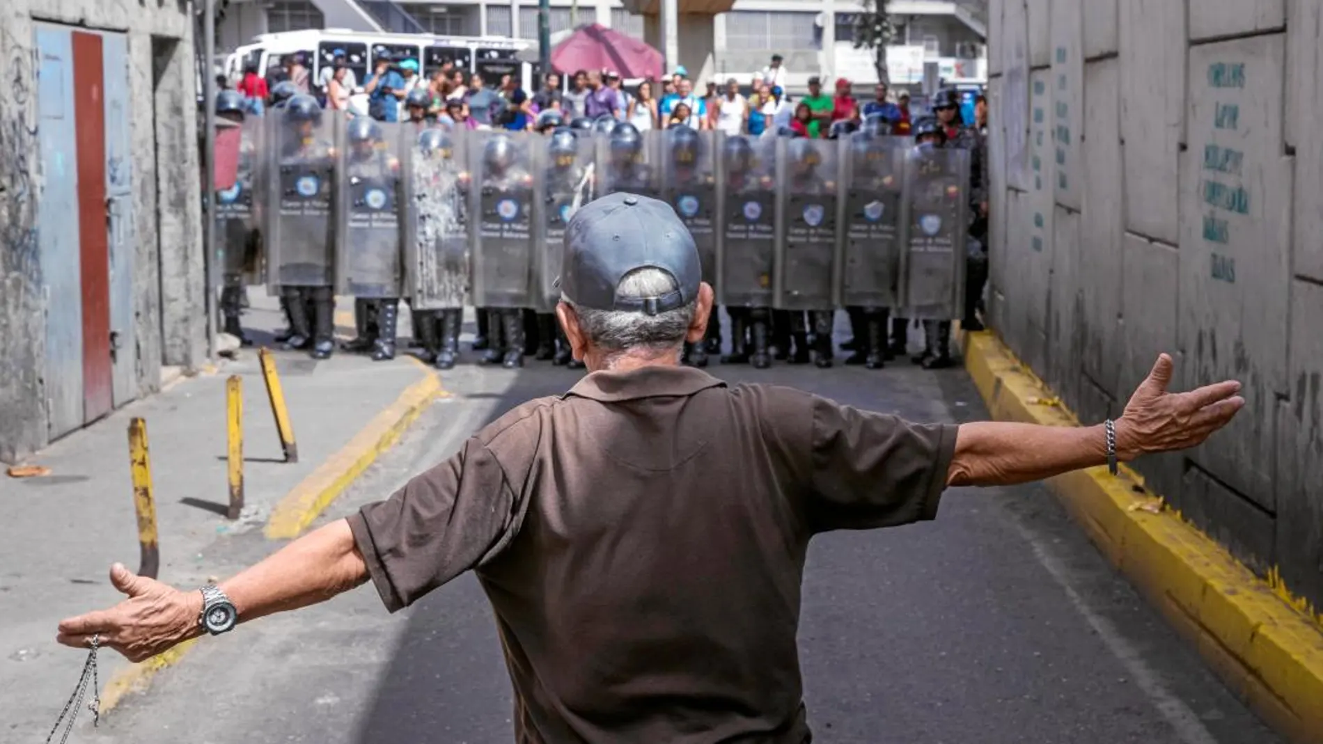 Un hombre protesta ayer en las calles de Caracas frente a la Policía Bolivariana en una manifestación por la falta de alimentos y los cortes de gas, agua y electricidad que sufren varias zonas del país. También la gasolina ha sido racionada y escasea el dinero en efectivo