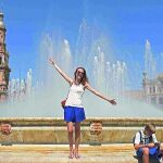 Unos turistas se refrescan en la fuente de la Plaza de España en Sevilla.