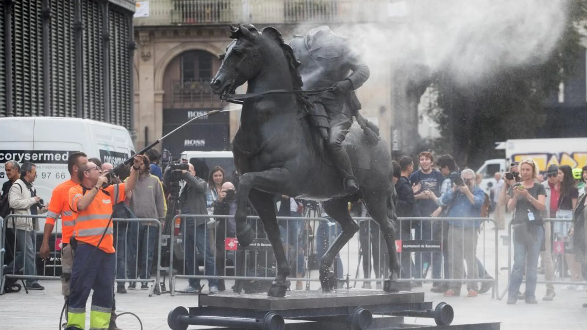 Operarios limpian la escultura de Franco, sobre la que manifestantes habían arrojado pintura.