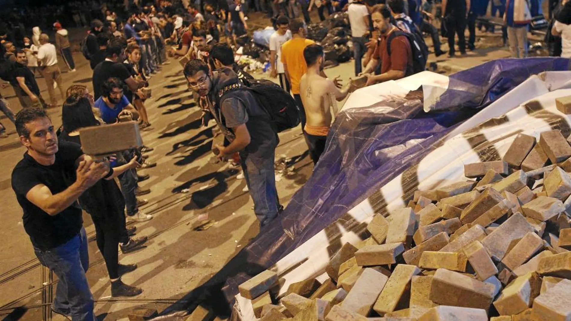 Cientos de jóvenes turcos trasladan piedras para levantar una barricada en la plaza de Taksim, anoche, en Estambul