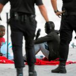 Dos inmigrantes descansan tras desembarcar de un bote en el puerto de Málaga