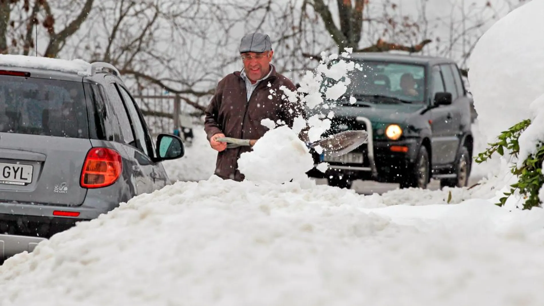 Un vecino del pueblo de Pajares trata de sacar su coche tras la nevada de esta mañana / Foto. Efe
