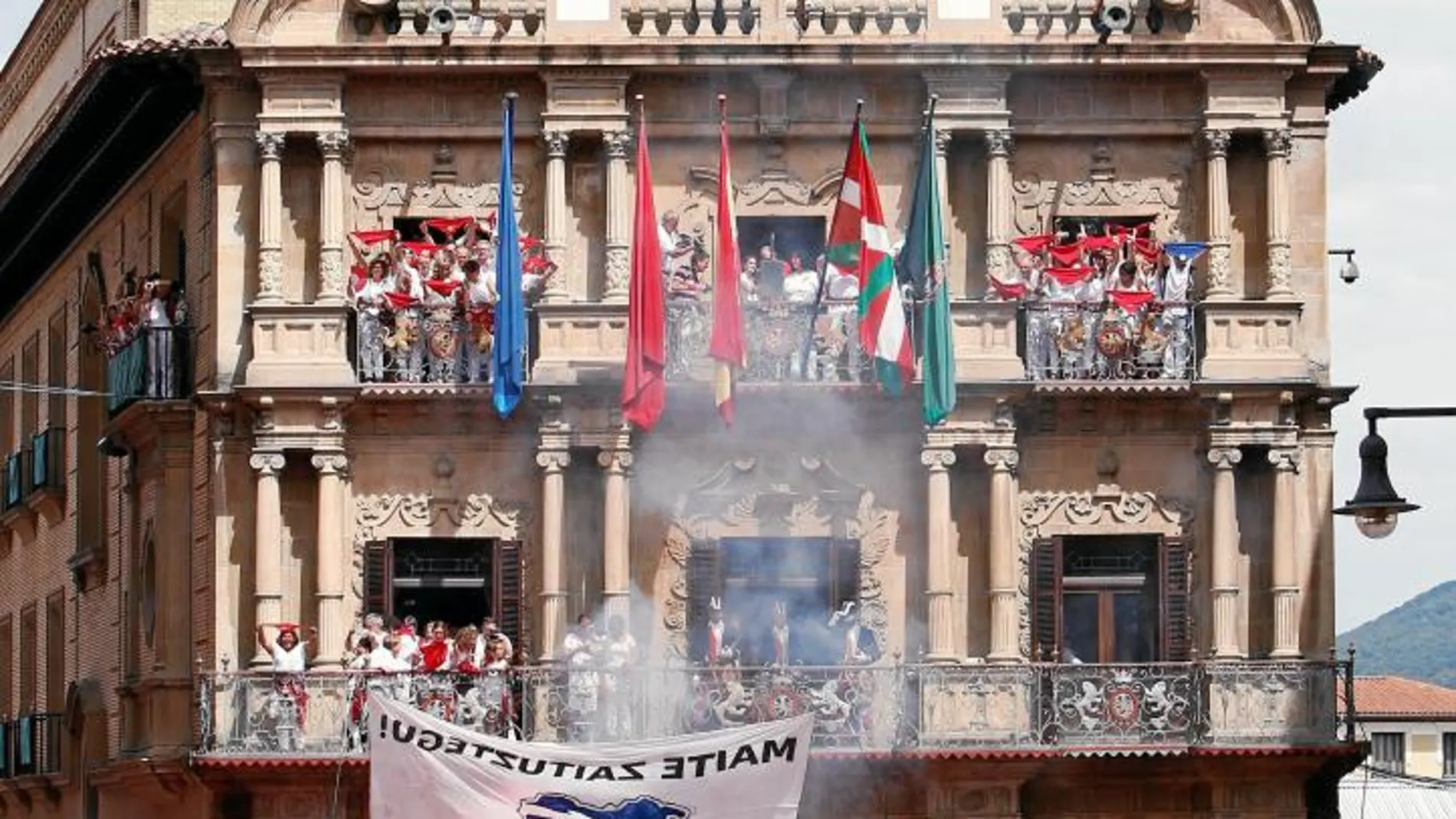 El arranque de los últimos Sanfermines, con la ikurriña en el balcón del Ayuntamiento de Pamplona y un cartel para el acercamiento de los presos etarras entre el público