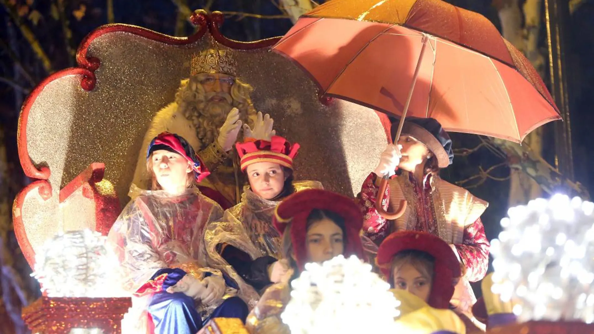 El Rey Melchor saluda desde su carroza, protegido bajo un paraguas de la incesante lluvia que cayó en Valladolid