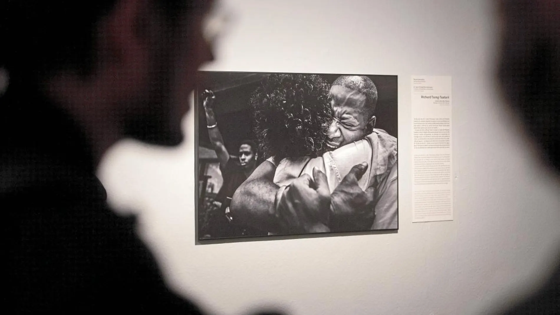 Dos personas contemplan una de las fotografías de la exposición, obra de Richard Song.