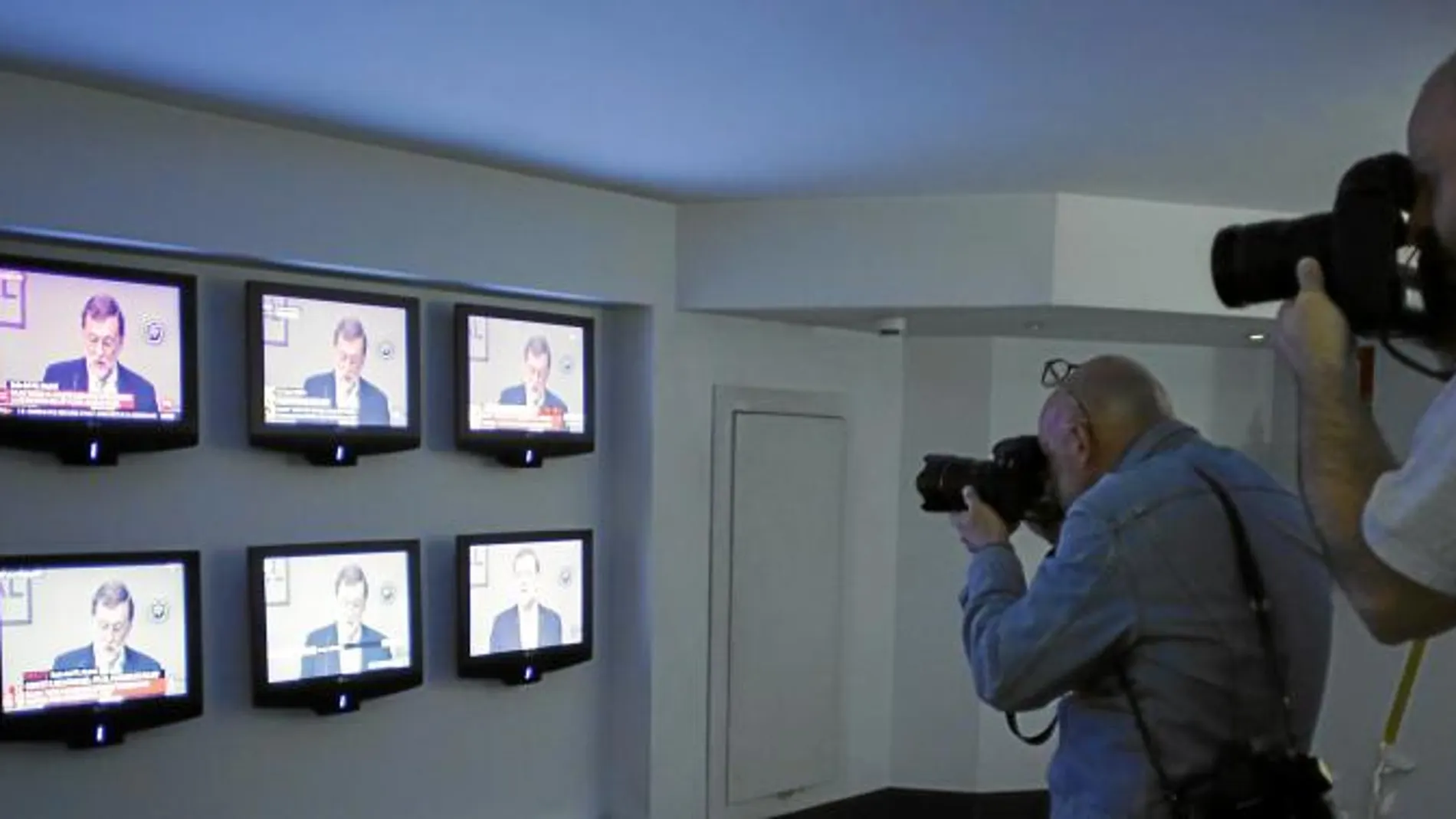 Varios fotógrafos en la sede de Génova inmortalizan el momento en que Rajoy anuncia en las pantallas su dimisión como presidente del partido / Javier Fdez.Largo