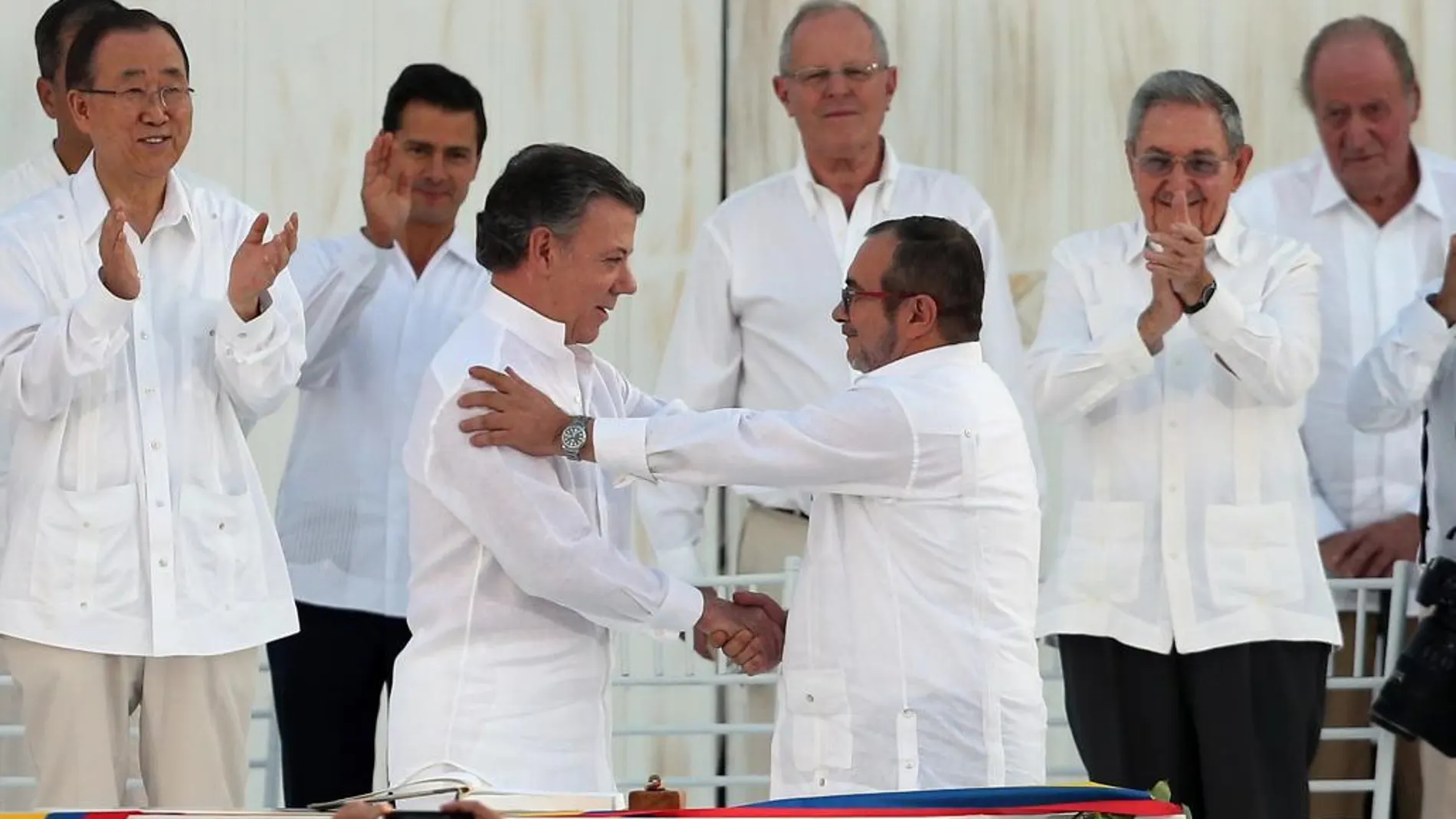 El presidente de Colombia, Juan Manuel Santos y el jefe de las FARC, Rodrigo Londono, alias Timochenko, se saludan tras la firma del acuerdo de paz