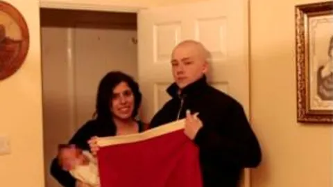 La pareja británica condenada posa con su bebé junto con una bandera nazi / EFE
