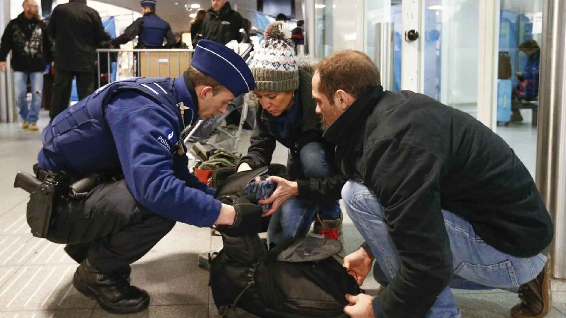 Un agente de policía belga registra el equipaje de dos pasajeros en la estación de trenes Midi de Bruselas la pasada Nochebuena