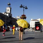 Tres guías de uno de los 'Free walking tour' que se organizan en Madrid esperan en la Puerta del Sol