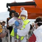 On voluntario ayuda a desembarcar a un bebé rescatado de una patera en el mediterráneo