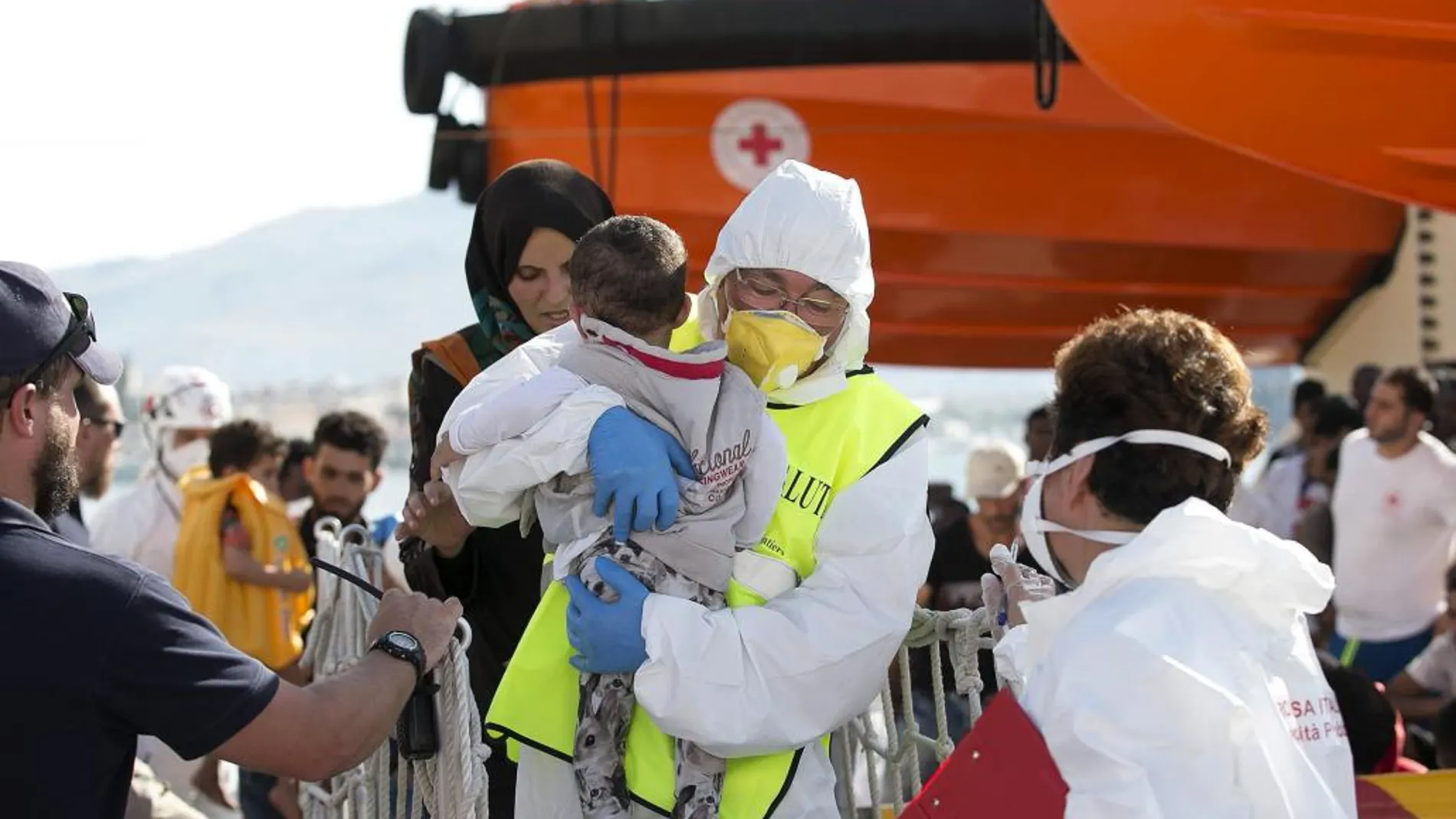 On voluntario ayuda a desembarcar a un bebé rescatado de una patera en el mediterráneo