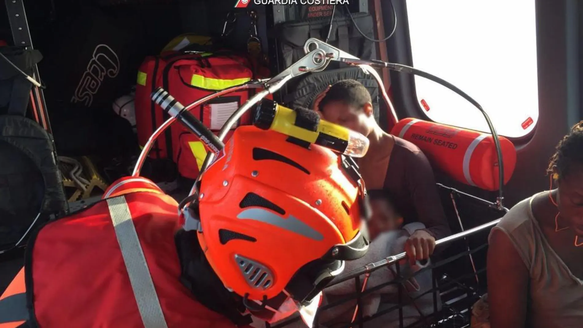 Una mujer y su hijo en un helicóptero de la Guardia Costera italiana tras ser rescatados en el Mar Mediterráneo