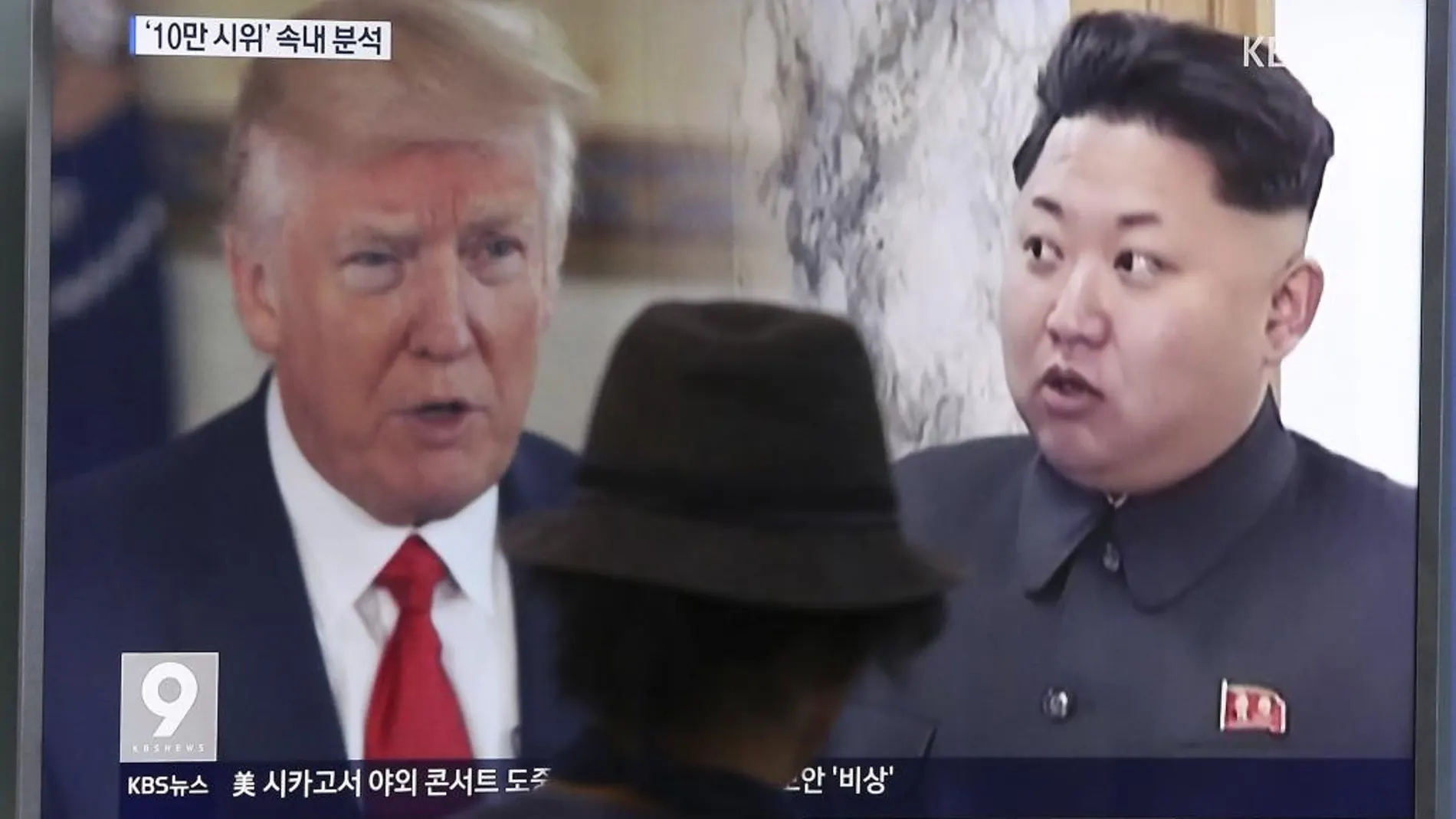 Un hombre observa una pantalla de televisión que muestra al Trump y a Kim Jong Un