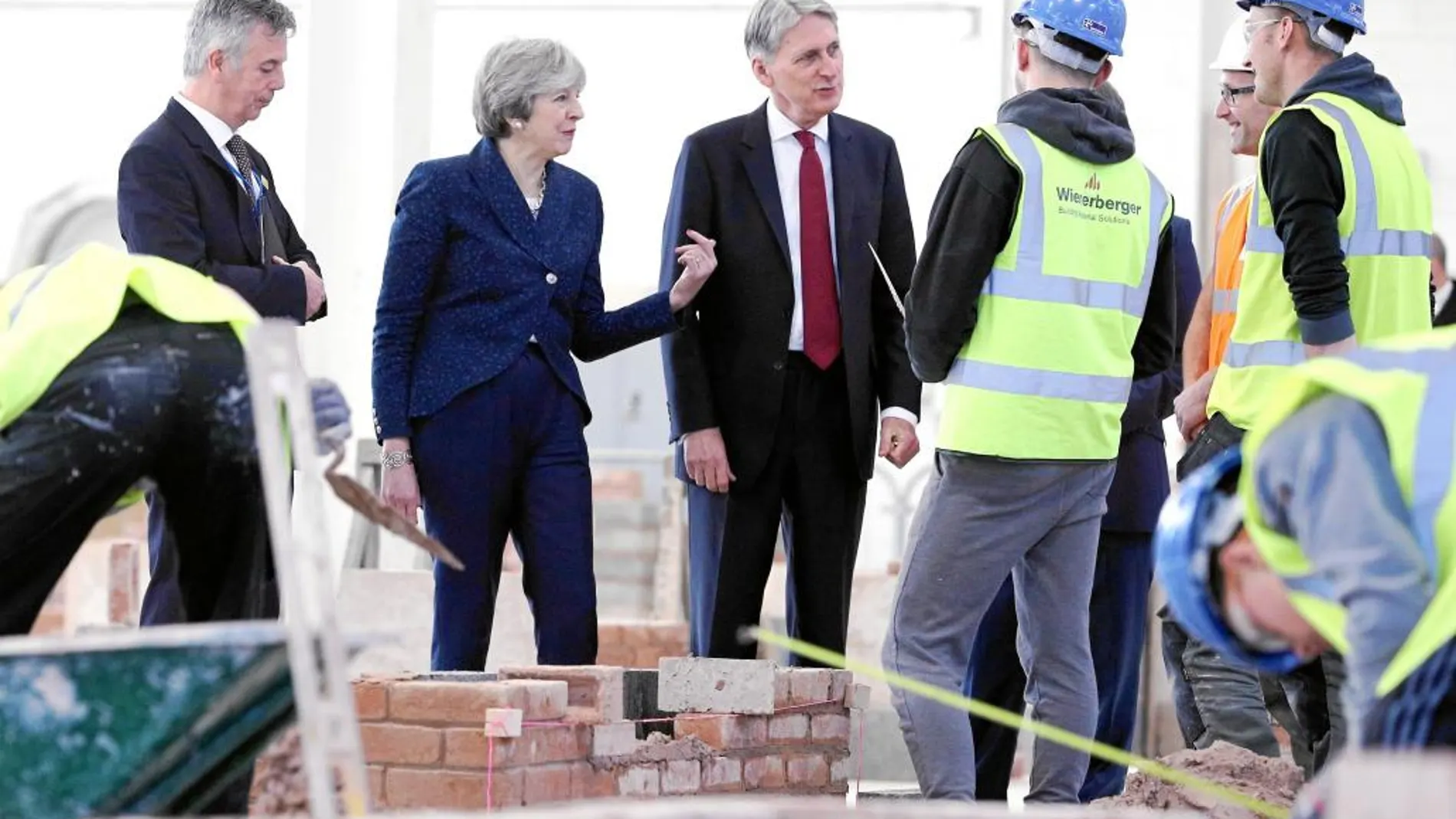 La primera ministra británica, Theresa May, y el ministro de Economía, Philip Hammond, visitan las obras del Leeds College of Building, ayer