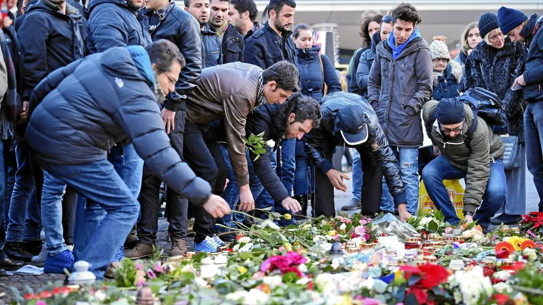 HOMENAJE A LAS VÍCTIMAS. Refugiados del centro de Tempelhof depositan flores por los fallecidos