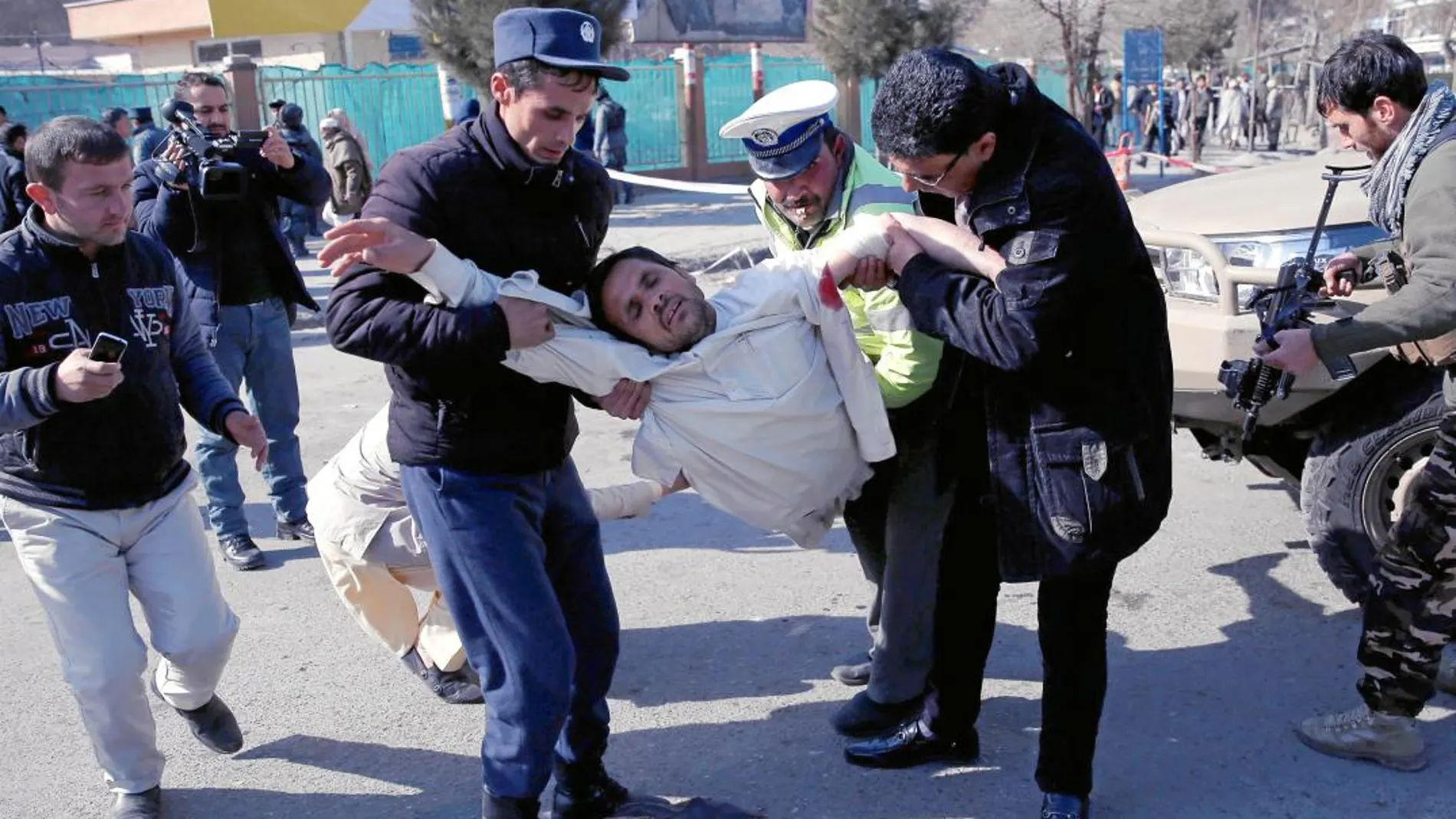 Un hombre traslada a un herido a una zona segura después del atentado, ayer, en Kabul