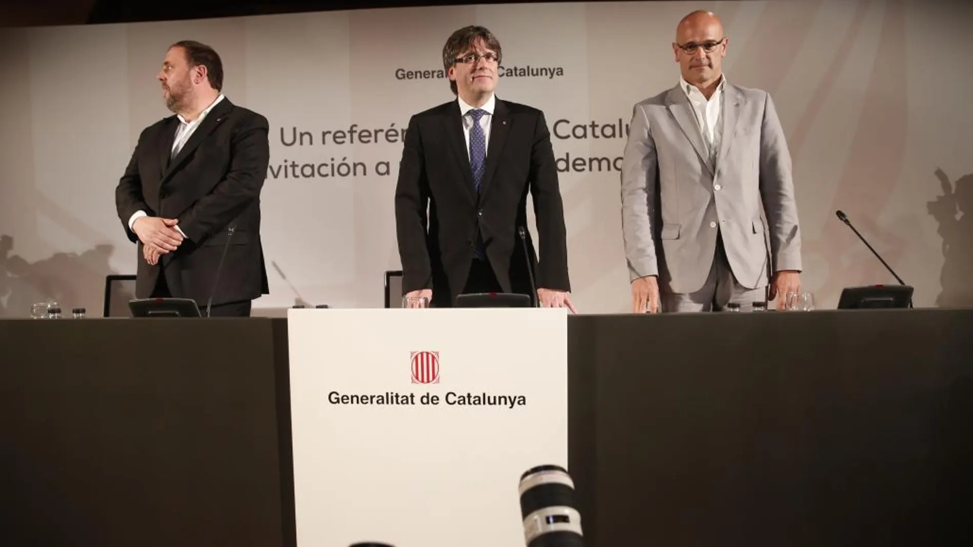 El presidente de la Generalitat, Carles Puigdemont, en presencia del vicepresidente, Oriol Junqueras, y el consejero de Asuntos Exteriores, Relaciones Institucionales y Transparencia, Raúl Romeva