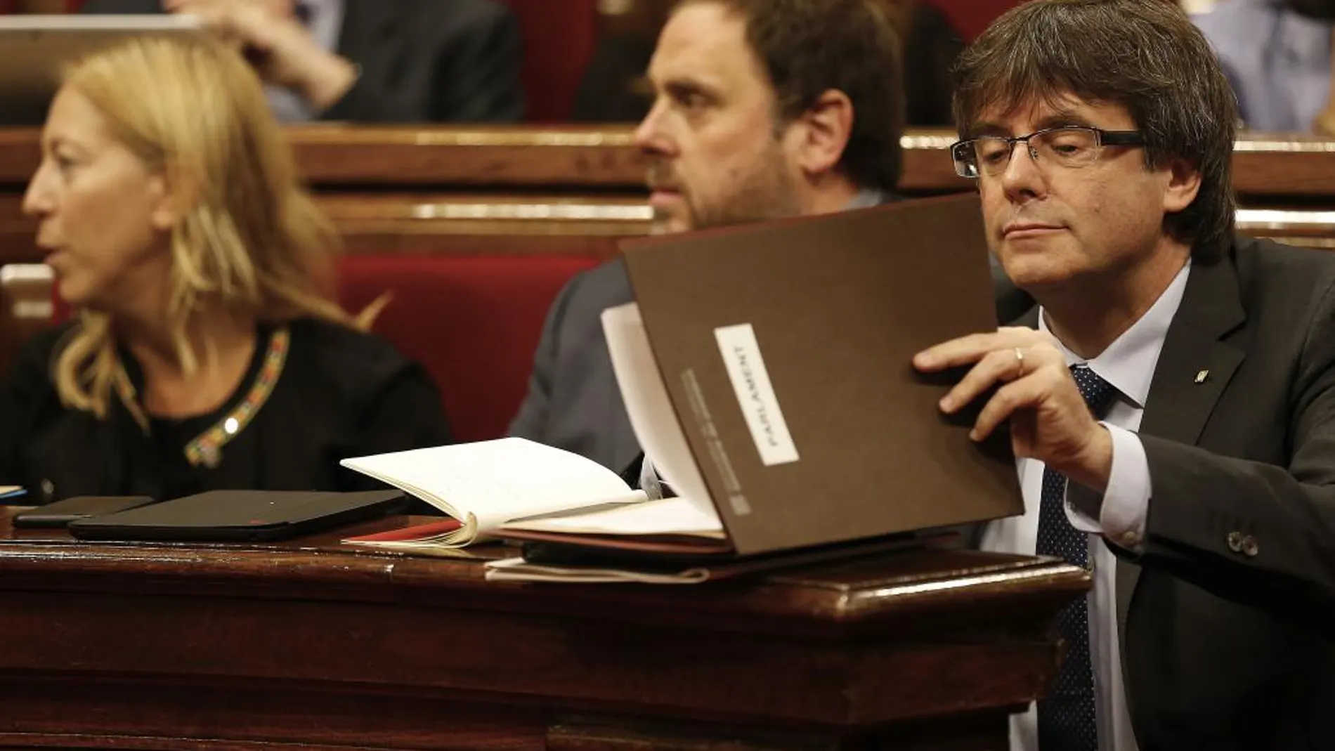 El presidente de la Generalitat, Carles Puigdemont, ordena unos apuntes hoy durante la sesión de control en el Parlament de Cataluña