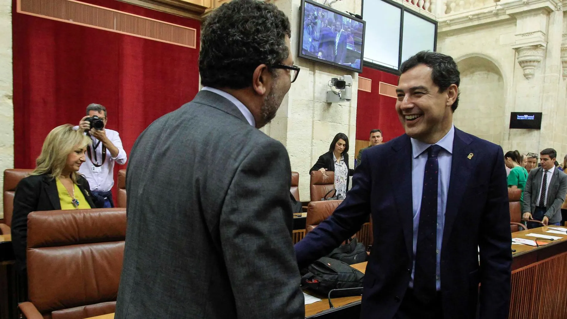 El presidente del Gobierno andaluz, Juanma Moreno, saludó ayer antes del Pleno al portavoz parlamentario de Vox, Francisco Serrano / Foto: Manuel Olmedo
