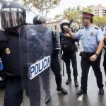 Agentes antidisturbios de la Policía Nacional y de los Mossos d' Esquadra discuten frente al Instituto Can Vilumara de L'Hospitalet de Llobregat