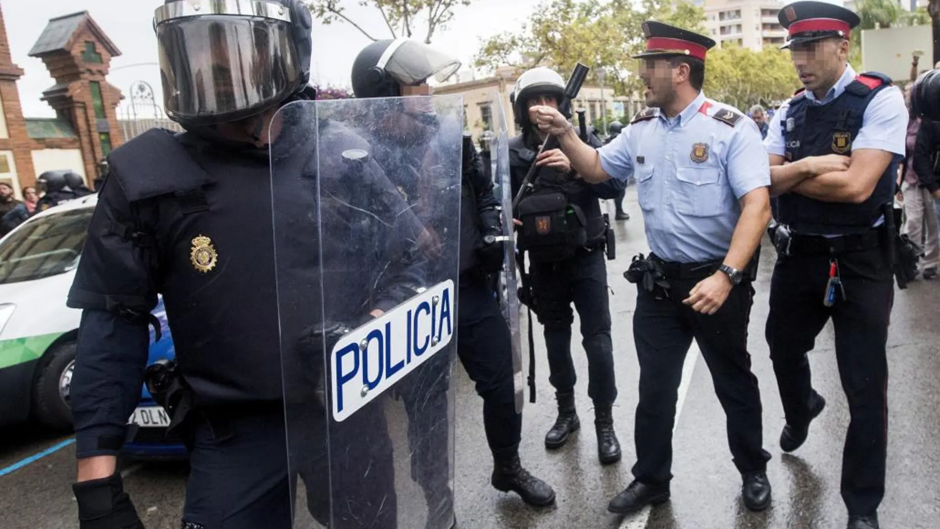 Agentes antidisturbios de la Policía Nacional y de los Mossos d' Esquadra discuten frente al Instituto Can Vilumara de L'Hospitalet de Llobregat