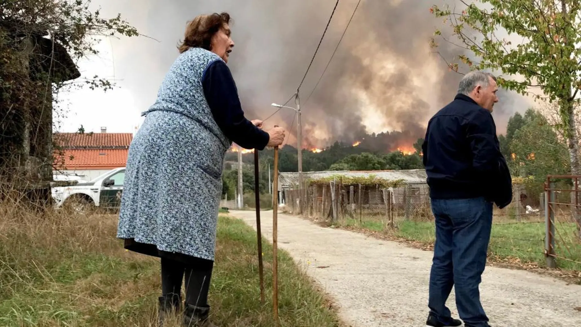 Dos vecinos junto a un incendio forestal esta mañana en las proximidades del municipio O Carballiño (Orense)