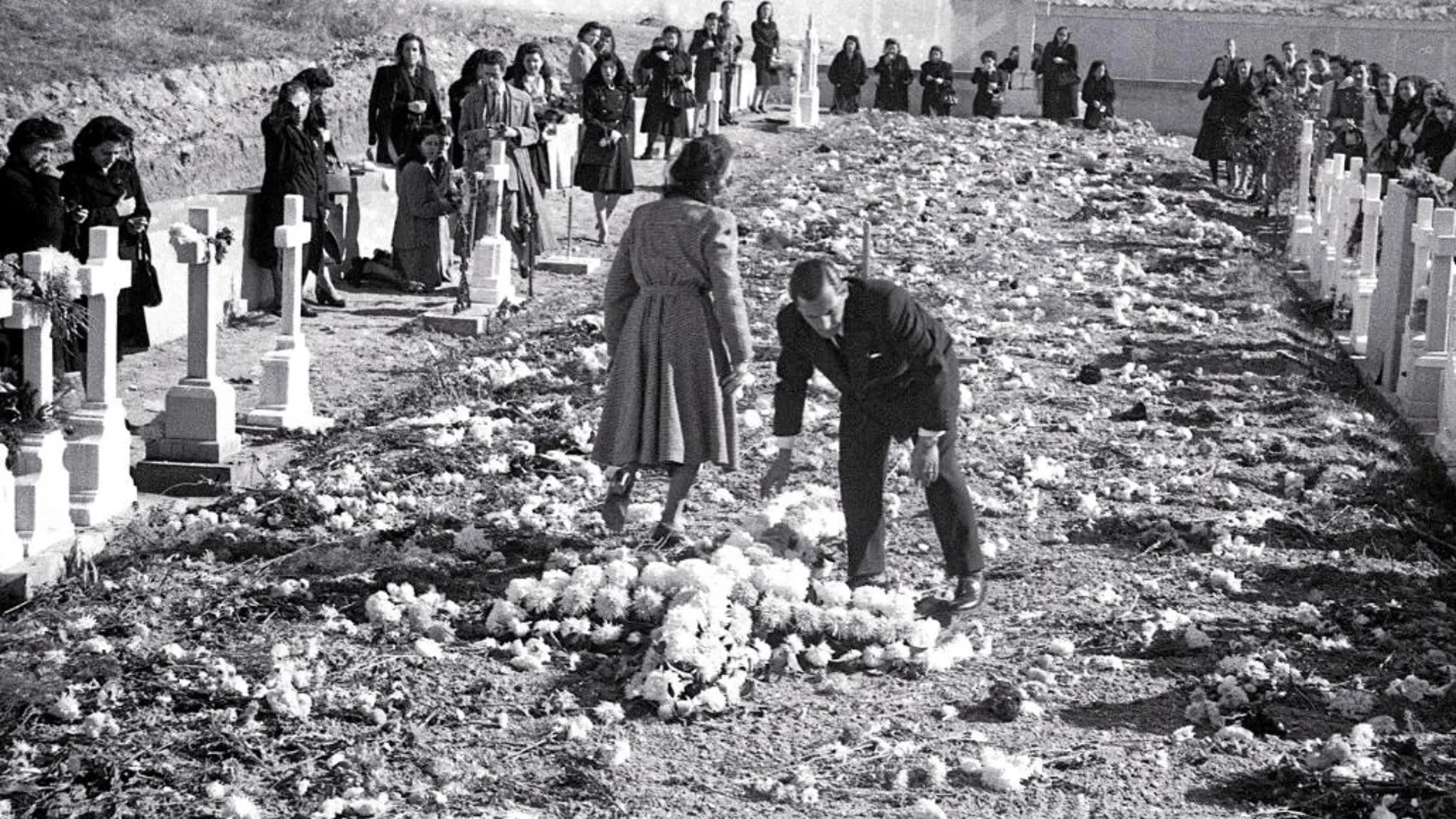 Varias personas dejan flores en Paracuellos, donde fueron asesinados y enterrados sus familiares