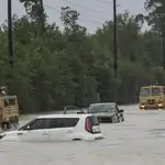 Camiones de la Guardia Nacional de Texas que llevan a víctimas de inundaciones pasan junto a vehículos sumergidos después del paso del huracán Harvey en Houston.