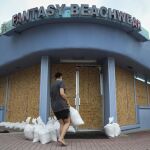 Miroslava Roznovjakova coloca sacos de arena frente a la puerta de su establecimiento, protegido por paneles de madera en las ventanas, en Daytona Beach, Florida