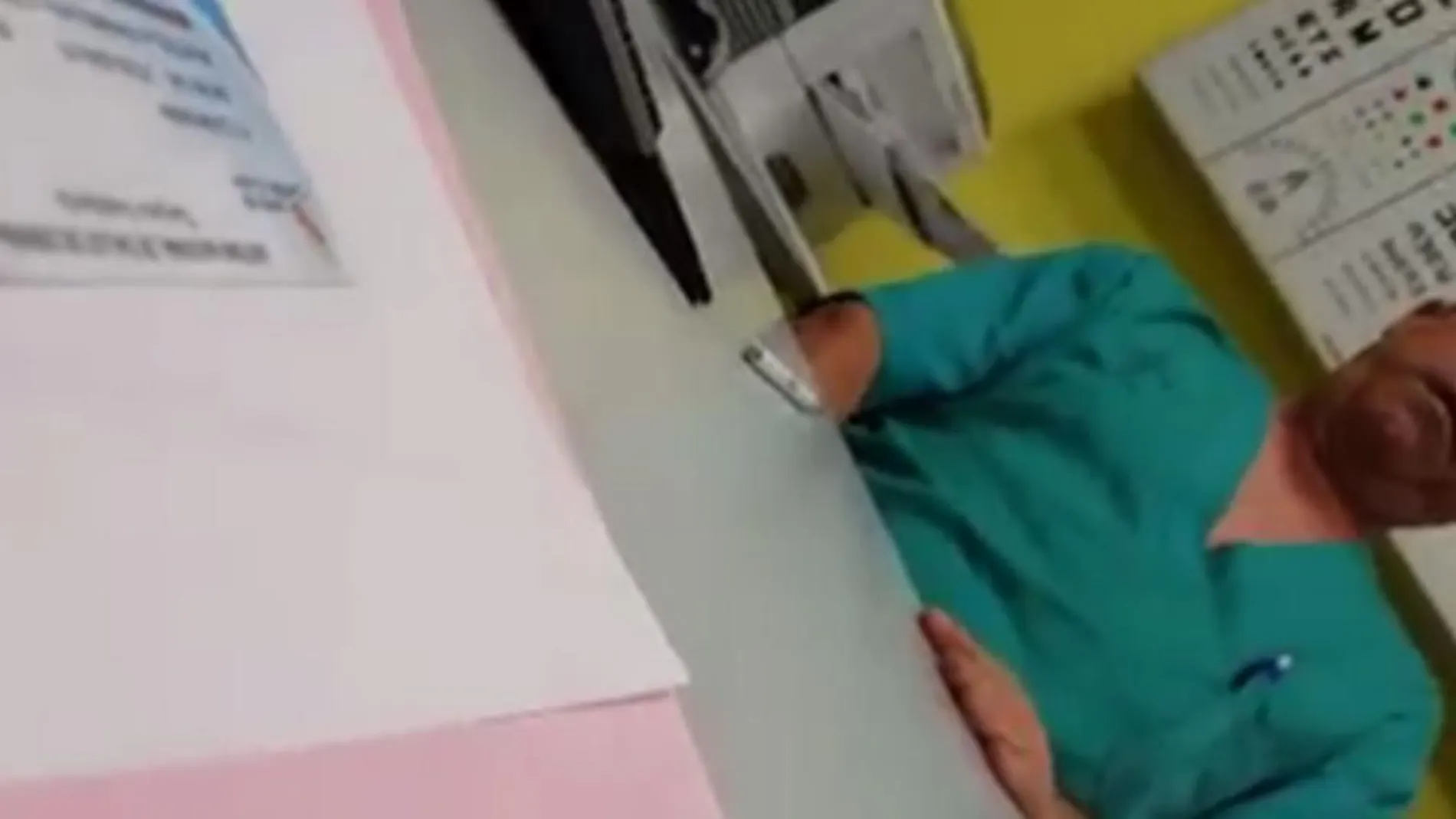Fotograma del vídeo, en el que el médico se masturba con la mano debajo de la mesa mientras la paciente está sentada enfrente