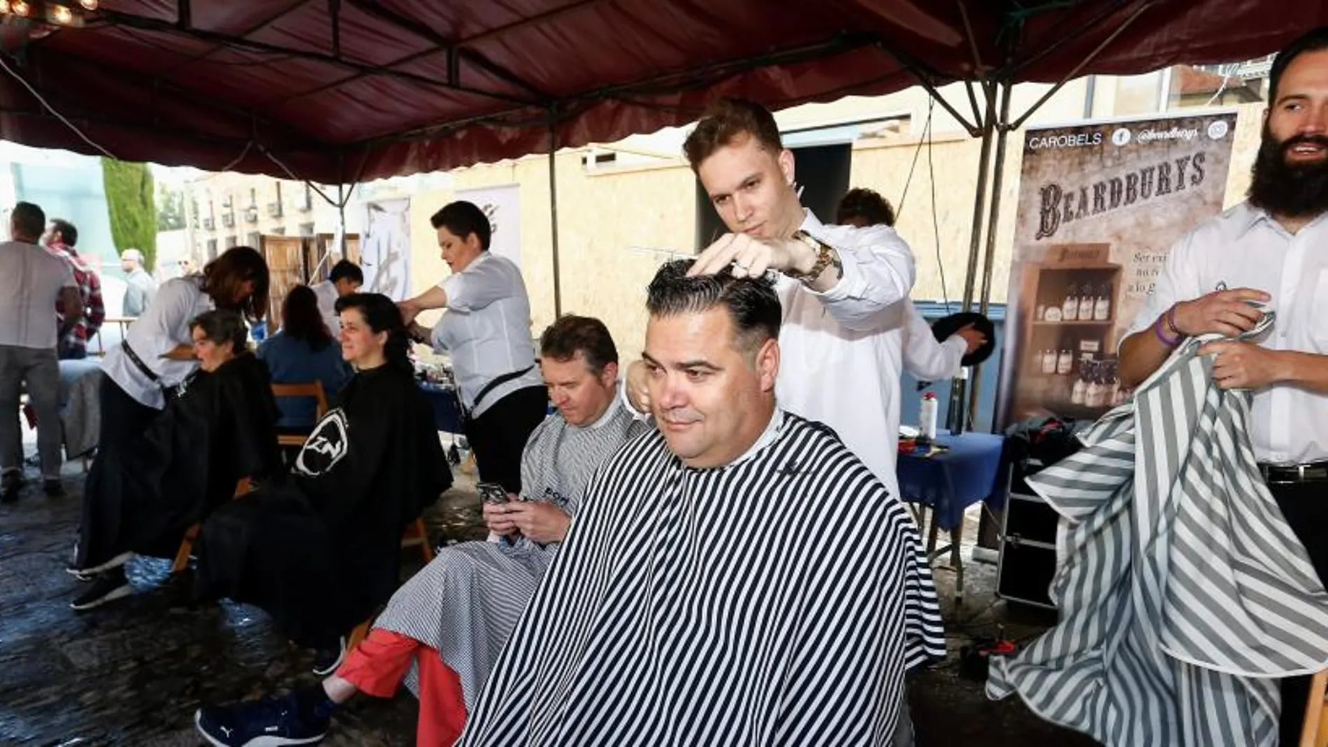 Carpa con peluqueros cortando el pelo en la Plaza San Marcelo