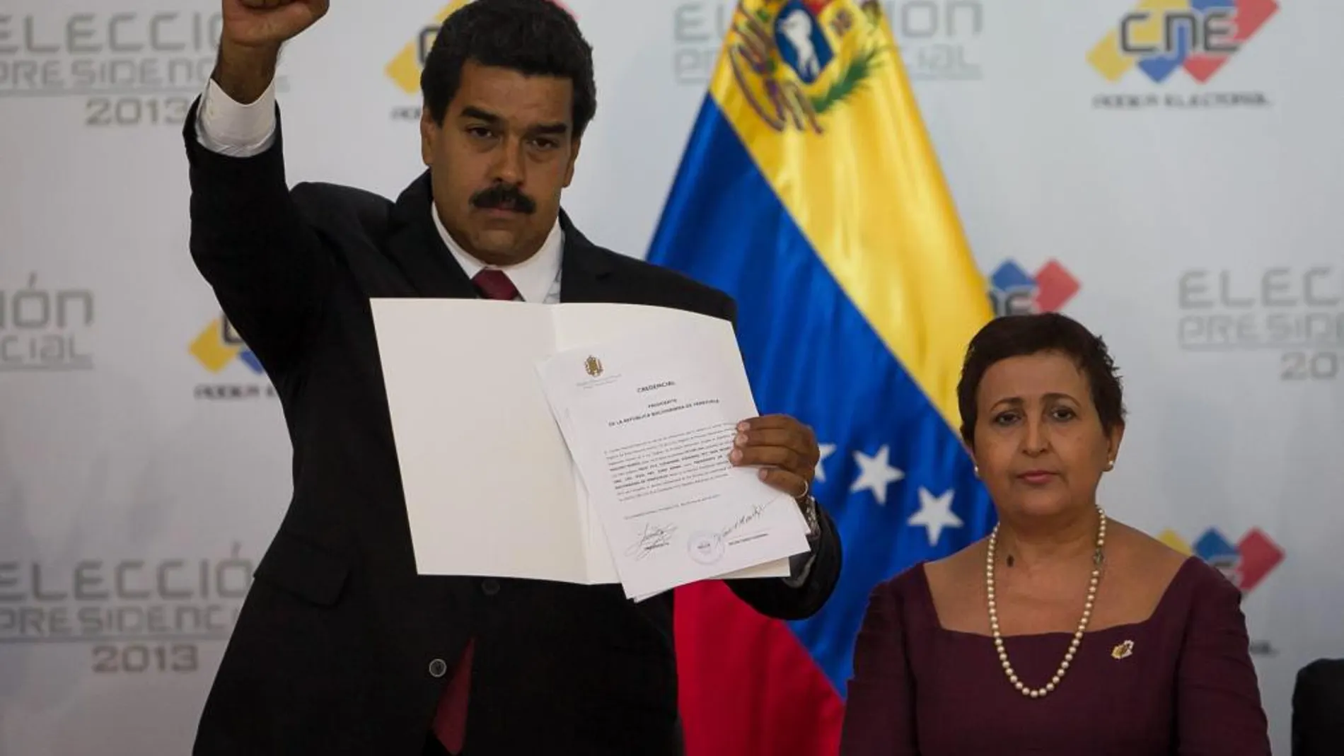 El gobernante encargado y candidato del oficialismo, Nicolás Maduro, saluda tras ser proclamado como presidente de Venezuela ante el Consejo Nacional Electoral junto a la directora del orgaismo, Tibisay Lucena