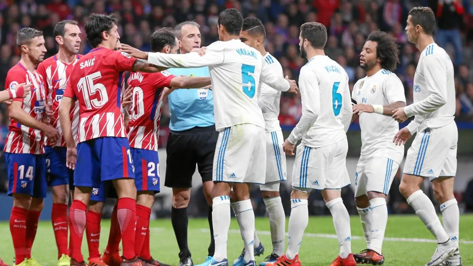 Los jugadores del Atlético y del Madrid protestan una decisión a Fernández Borbalán