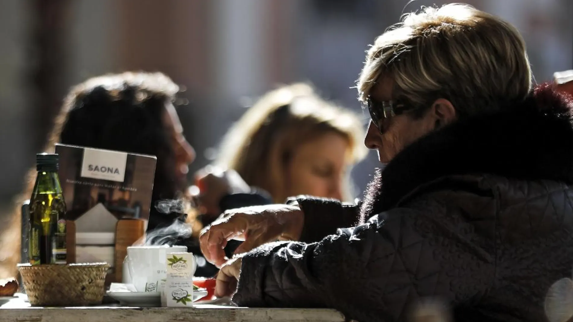 Una mujer disfruta de una bebida caliente durante la mañana de hoy cuando las temperaturas mínimas de la pasada madrugada han sufrido un descenso de entre tres y diez grados sobre las de ayer en varios puntos de la Comunitat Valenciana