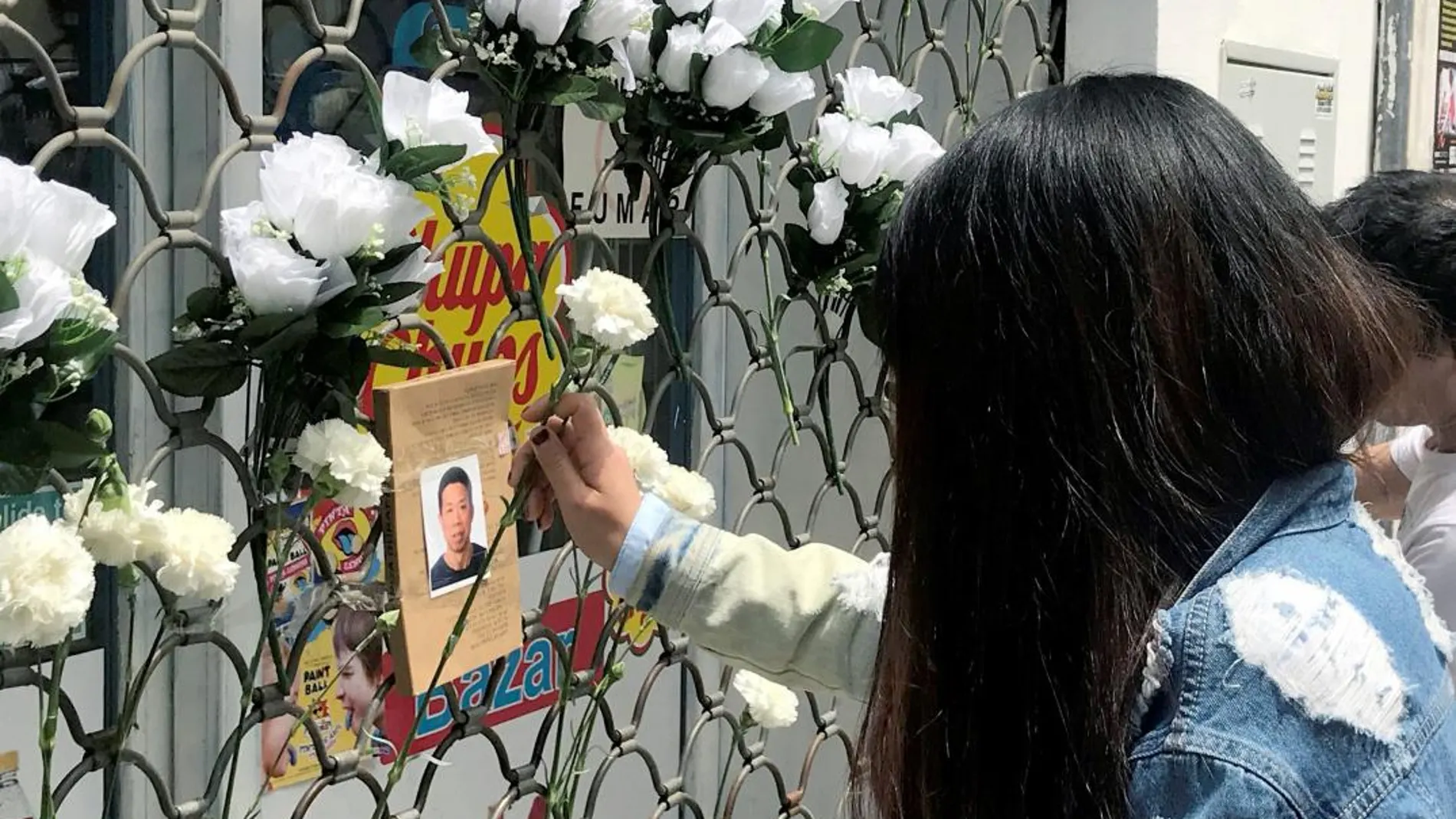 Una mujer coloca una flor ante la foto del ciudadano chino asesinado anoche en Carmona (Sevilla) / Foto: Efe
