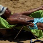 Un hombre toma el sol en la playa de Gijón/Reuters
