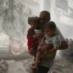 Un hombre huye con varios niños después de un ataque aéreo en Douma