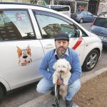 Mario con su perro, junto a su vehículo adaptado para el traslado de mascotas, en Madrid