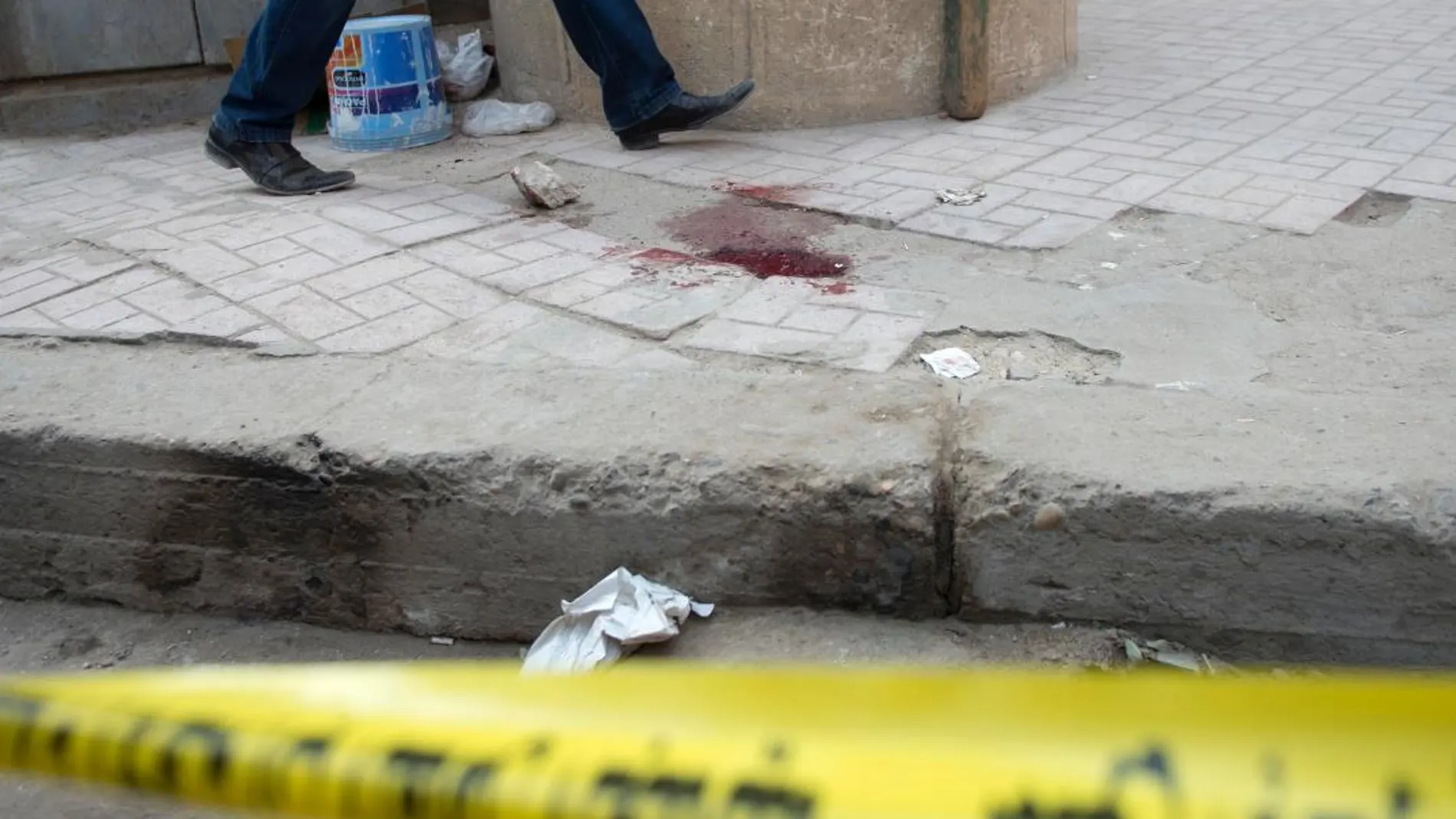 Un miembros de las Fuerzas de Seguridad pasa junto a una mancha de sangre junto a la iglesia Mar Mina tras el ataque contra el templo en el distrito de Heluán, en el sureste de El Cairo (Egipto) el pasado 29 de diciembre