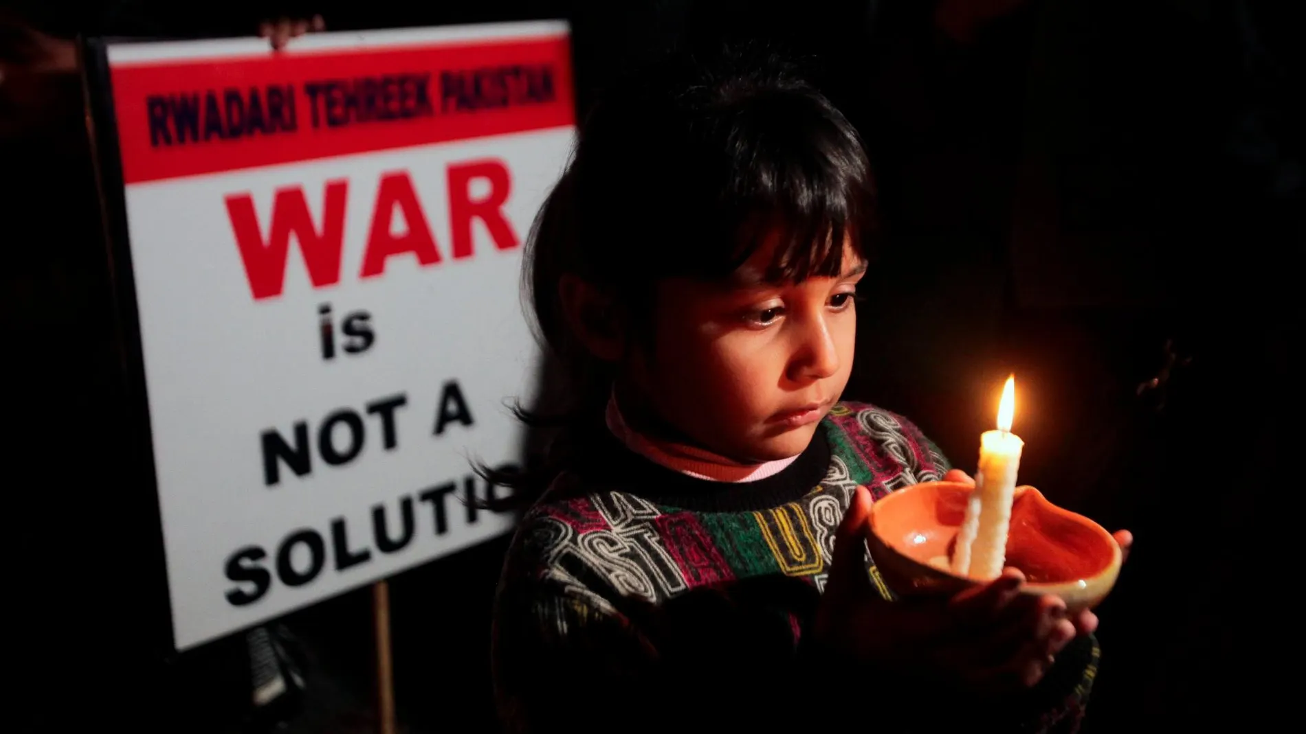 Un niño sostiene una vela en señal de protesta por la crisis entre Pakistán e India/Reuters