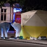 Oficiales de policía investigan en la escena donde una mujer murió y varias personas resultaron heridas por un sospechoso ataque con cuchillo