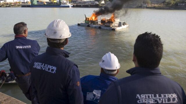 Trabajadores de Astilleros de Sevilla durante la protesta que protagonizaron en 2009 en el río Guadalquivir, donde decidieron cortar el cauce del río mediante la botadura de una barcaza llena de contenedores con material inflamable, a la que se le prendió fuego, lo cual provocó el corte del tráfico fluvial a la altura de la factoría, en el llamado muelle de armamento, para reivindicar una solución a los problemas de esta empresa (Foto: Efe)