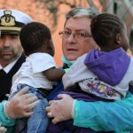 Un médico lleva en brazos a dos niños rescatados ayer por buque noruego Siem Pilot