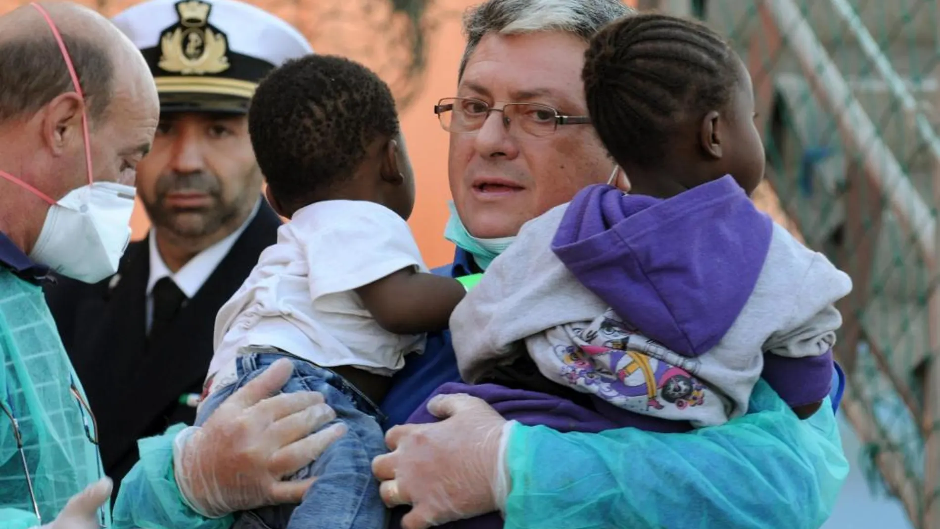 Un médico lleva en brazos a dos niños rescatados ayer por buque noruego Siem Pilot